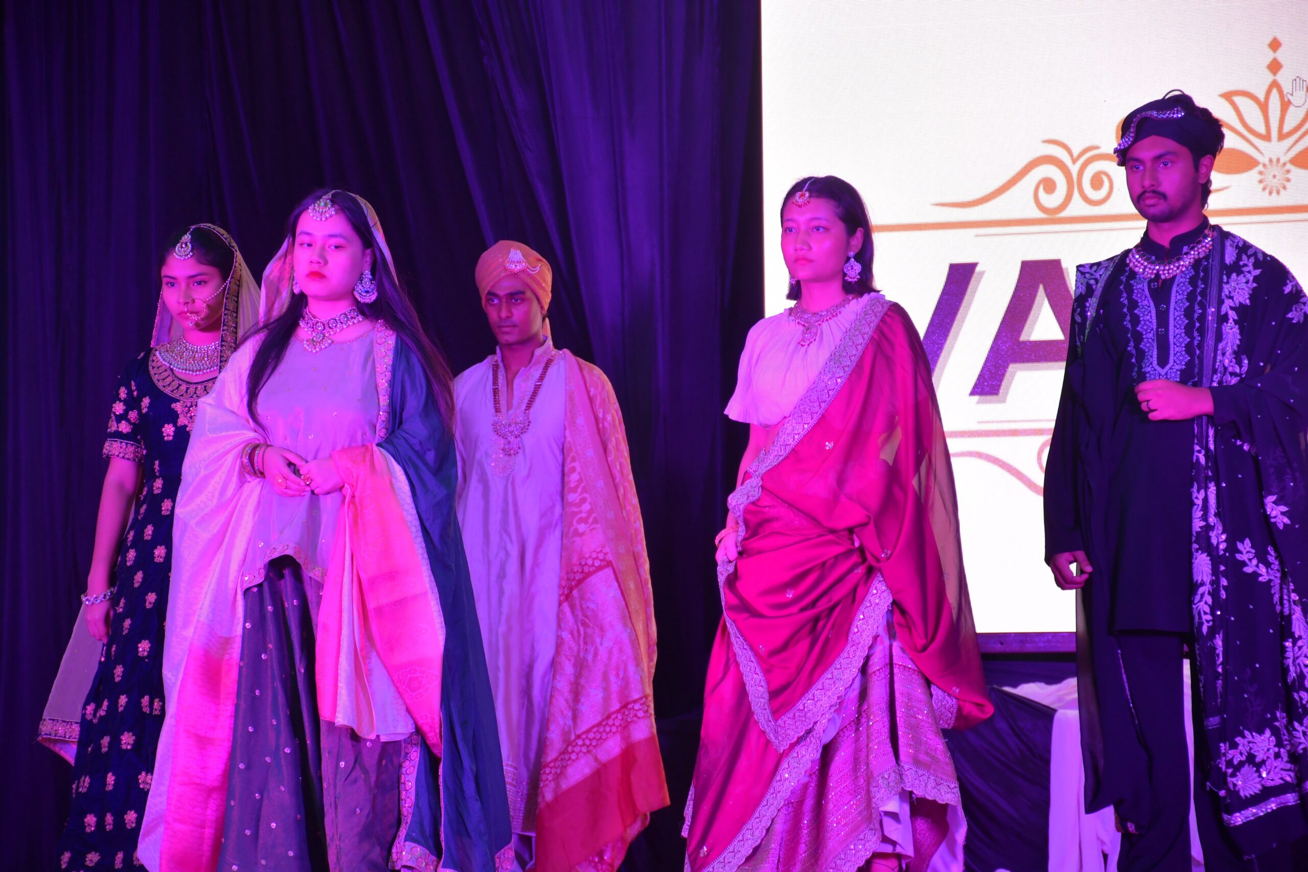 Students in traditional dress on stage at an RCMB celebration