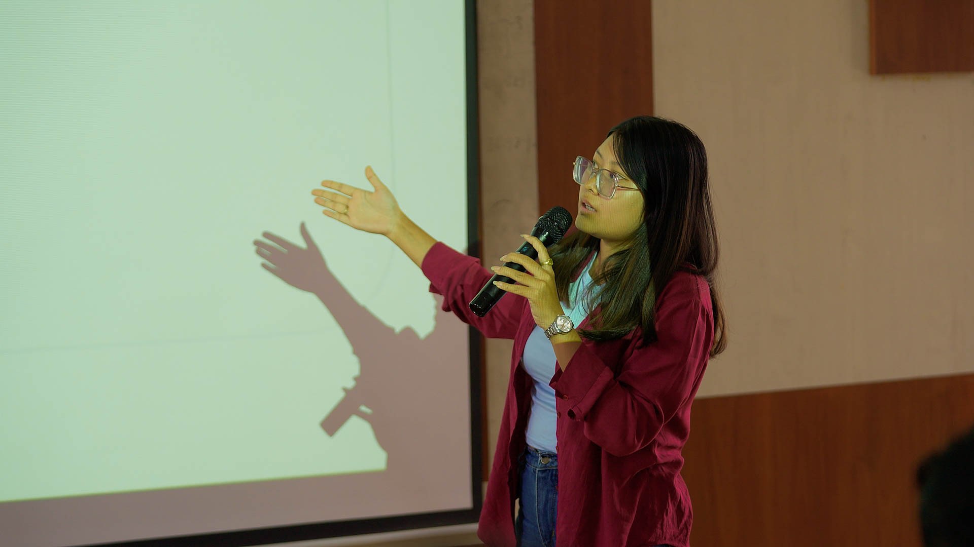 RCMB student presenting with a microphone and projected slides