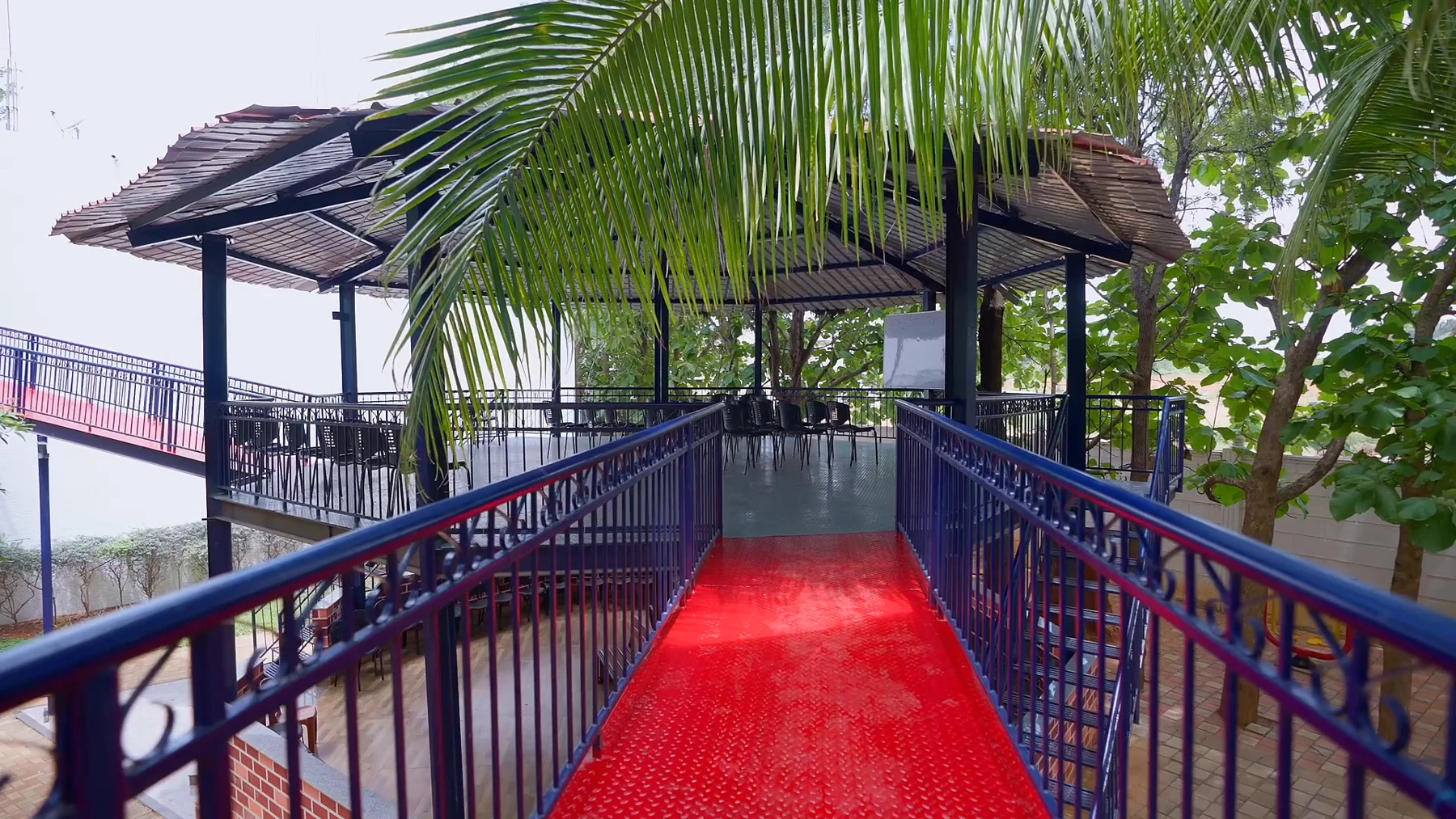 Open-air classrooms at RCMB, reached by a red walkway among palms
