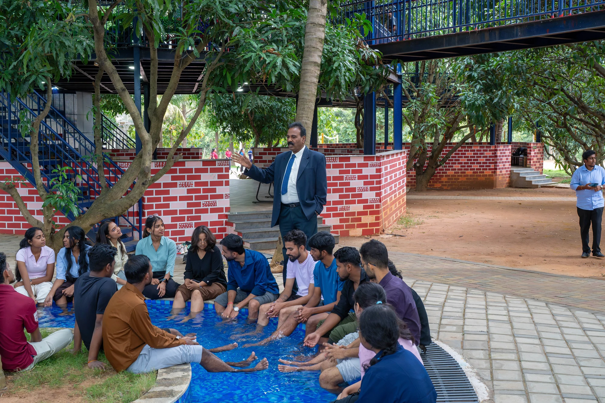 RCMB students and a faculty member in an outdoor discussion beneath campus trees